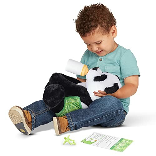 Young child feeding a stuffed panda with a toy bottle.