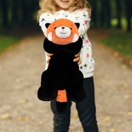 Child holding a red panda plush toy on a path