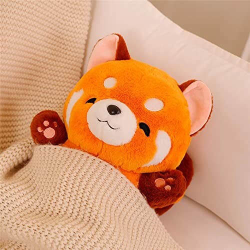 Cute red panda plush toy tucked in bed.