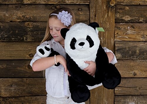 Girl holding two panda plush toys against a wooden wall.