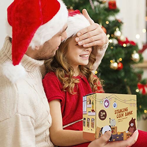 Person and child in Santa hats exchanging a gift near a Christmas tree.