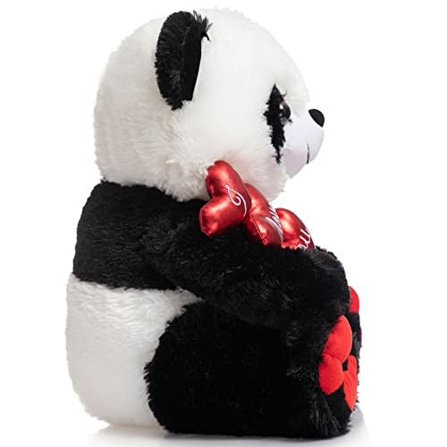 Side view of a plush panda bear holding red hearts