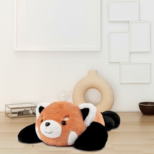 Red panda plush toy on a wooden surface with modern decor.