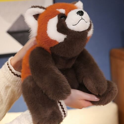 Person holding a red panda plush toy.