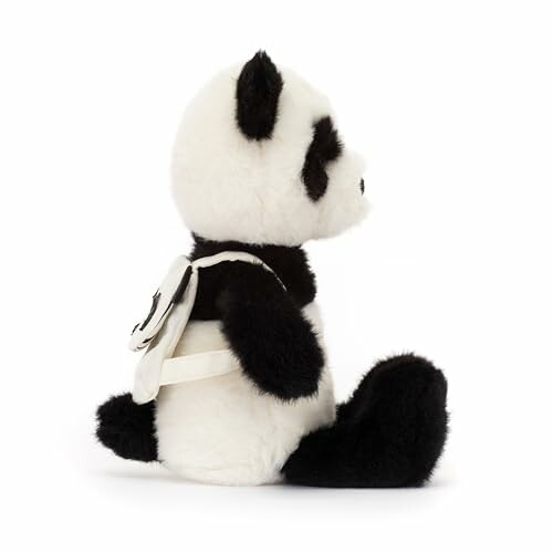 Side view of a stuffed panda toy wearing a small backpack.