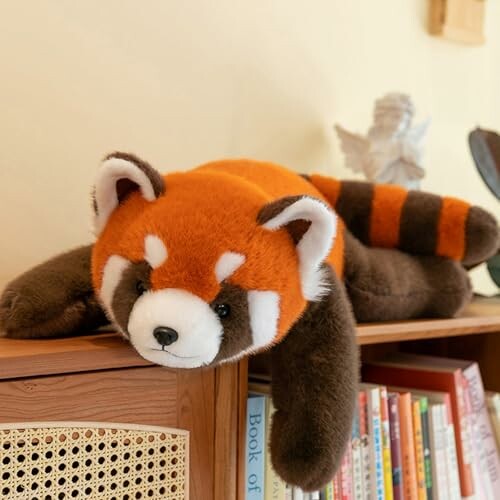 Stuffed red panda toy lying on a shelf.